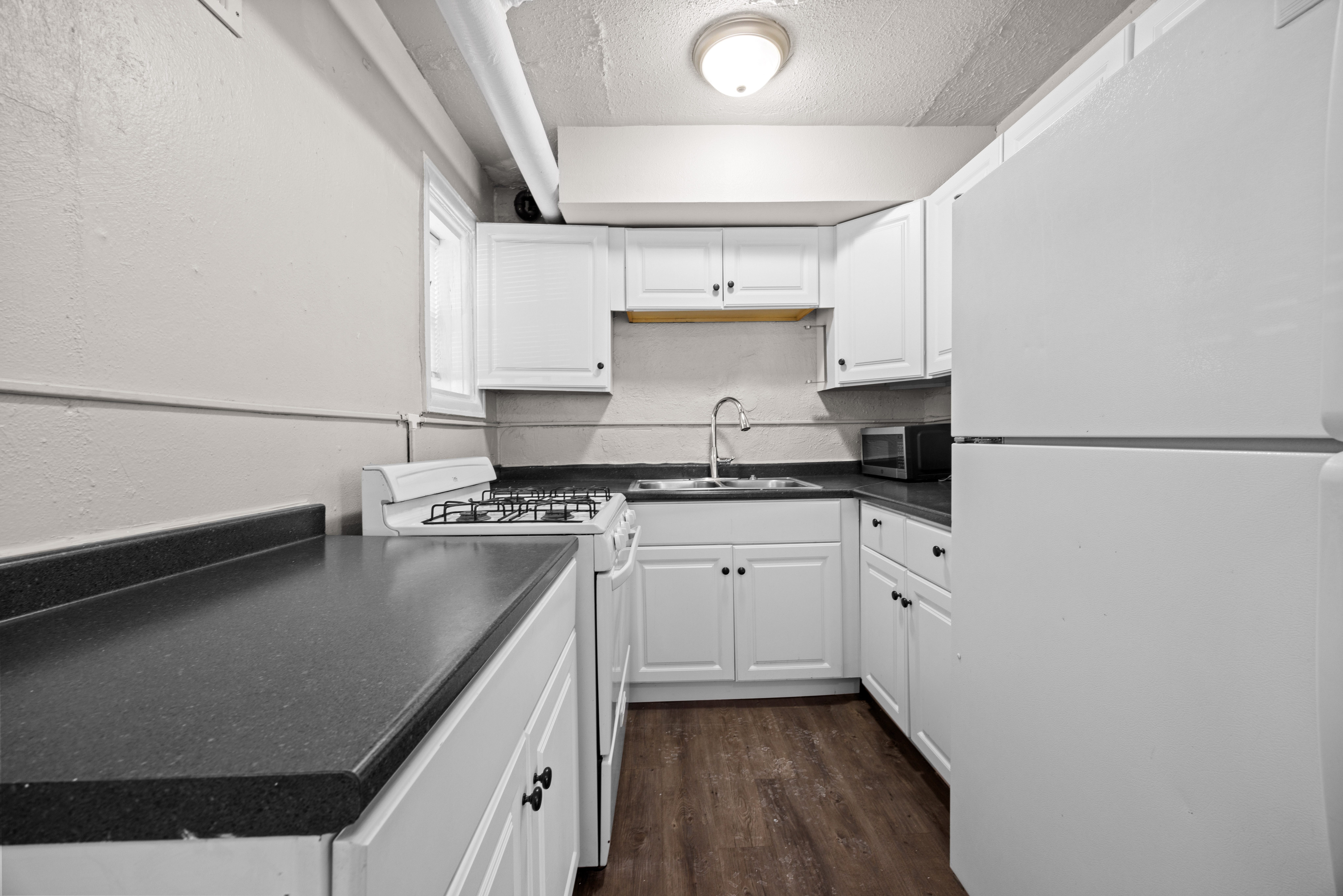 A kitchen with white cabinets and a black countertop.